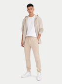 Person wearing a beige tracksuit with a white shirt on a white background #color_beige