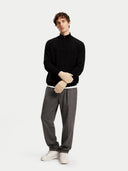 Man wearing a black turtleneck, gray pants, and white shoes on a white background #color_beige