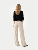back view of a person wearing a black top and beige pants on a white background #color_black