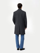 back view of a man wearing a black coat and blue jeans on a white background #color_charcoal