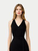 close up front view of a woman wearing a black sleeveless dress with belt on a light gray background #color_black