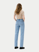 back view of a person wearing light blue jeans and a beige top on a white background #color_beige