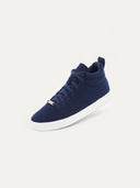 A high-top sneaker featuring a navy textured upper with matching navy laces and a small silver brand plate at the base of the tongue. The shoe has a padded collar, a pull tab at the heel, and a thick white rubber sole, shown from a three-quarter angle against a plain white background. #color_navy
