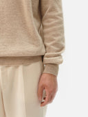 close up of a beige sweater sleeve and white pants #color_warm-grey