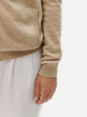 Beige sweater sleeve and white pants on a plain background #color_warm-grey
