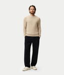 Front view of a man standing with a beige crew neckline sweater and black pants. shop men