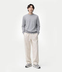 Front view of a man standing with a gray crew neckline sweater and white pants. shop men