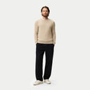 Front view of a man standing with a beige crew neckline sweater and black pants. shop men