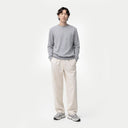 Front view of a man standing with a gray crew neckline sweater and white pants. shop men