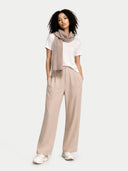 Woman wearing a white shirt, beige scarf, and beige pants on a white background #color_taupe