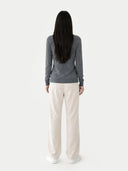 back view of a person wearing a gray sweater and white pants on a light gray background #color_plum-kitten