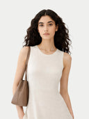 Woman holding a brown leather handbag against a white background #color_marshmallow
