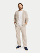 Man wearing a beige cardigan, white t-shirt, beige pants, and navy shoes on a white background #color_navy