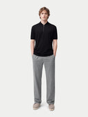 Person wearing a black polo shirt and gray pants on a white background #color_black