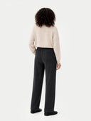 back view of a woman wearing a beige sweater and black pants on a white background #color_charcoal