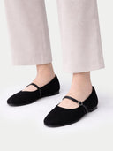 Black flat shoes worn with light-colored pants on a white background #color_black