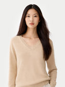 Woman wearing a beige sweater against a white background.