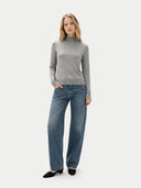 Woman wearing a gray mock neck sweater and blue jeans on a white background #color_high-rise