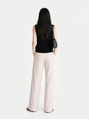 Back-view of a woman wearing a black sleeveless top and light pink wide-leg pants on a white background #color_black