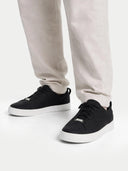 Black sneakers worn with light gray pants on a white background #color_black