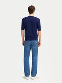 back view of man wearing a navy sweater and blue jeans on a white background #color_mood-indigo