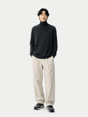 front view of a Person wearing a black turtleneck sweater and beige pants on a white background #color_charcoal