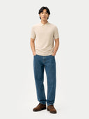 front view of a man wearing a beige polo shirt and blue jeans standing against a white background #color_marshmallow
