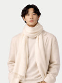 Person wearing a beige scarf and coat on a white background #color_off-white