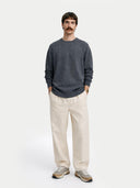front view of a Man wearing a dark gray crew neck sweater and beige pants on a white background #color_plum-kitten