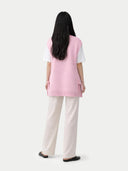 back view of a pink maternity top and white pants on a white background #color_almond-blossom