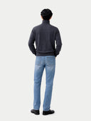 back view of a person wearing a dark gray turtleneck and light blue jeans on a white background #color_charcoal