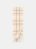 A cream and beige plaid scarf with fringe detailing, shown flat against a light gray background.