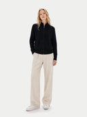 front view of a woman wearing a black zip-up cardigan and beige pants on a white background #color_black