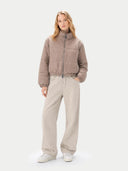 Woman wearing a beige puffer jacket and pants on a white background #color_taupe