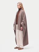 Model wrapped in the Cashmere Woven Blanket in Taupe, front view, blanket open