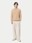 front view of Person wearing a beige sweater and white pants on a white background #color_beige