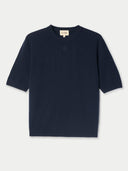 Navy blue short sleeve top with a brand label on a light gray background #color_navy-blazer