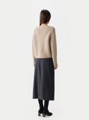 Back view of a woman wearing a beige cardigan and dark gray skirt on a white background #color_warm-grey