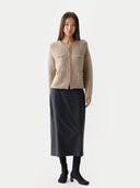 front view of a woman wearing a beige cardigan and black skirt on a white background #color_warm-grey