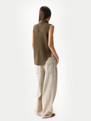 Back view of a person wearing a green sleeveless sweater and beige pants on a white background #color_cub