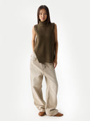 Woman wearing a brown sleeveless sweater and beige pants on a white background #color_cub
