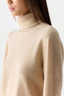 Close-up shot from the side. Beige turtleneck sweater worn by a person on a white background #color_beige