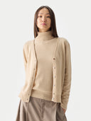 close up of a woman wearing a beige turtleneck sweater and v-neck cardigan on a white background #color_beige