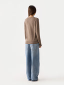 back view of a woman wearing a brown sweater and light blue jeans on a white background #color_taupe
