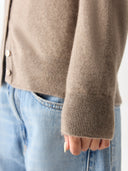 Close-up of brown sleeve details of cardigan and light blue jeans. #color_taupe