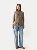 front view of woman wearing a brown V-neck cardigan over turtleneck sweater and light blue jeans on a white background #color_taupe