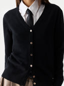 close up front view of a person wearing a black v-neck cardigan over a white shirt with a tie on a light gray background #color_black