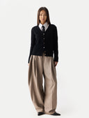 Person wearing a black v-neck cardigan, white shirt, and beige pants on a white background #color_black
