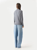 back view of a woman wearing a gray sweater and light blue jeans on a white background #color_dim-gray