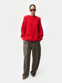 Person wearing a red sweater and brown pants on a white background #color_fiery-red